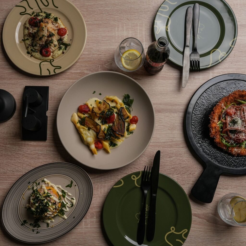 فيتالي V itlay طاولة عليها طبق باستا بالصوص الابيض وشرائح الباذنجان وطبق بيتزا لذيذ